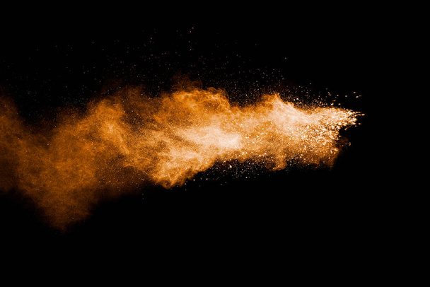 Orange color powder explosion on black background. - Foto, Imagen
