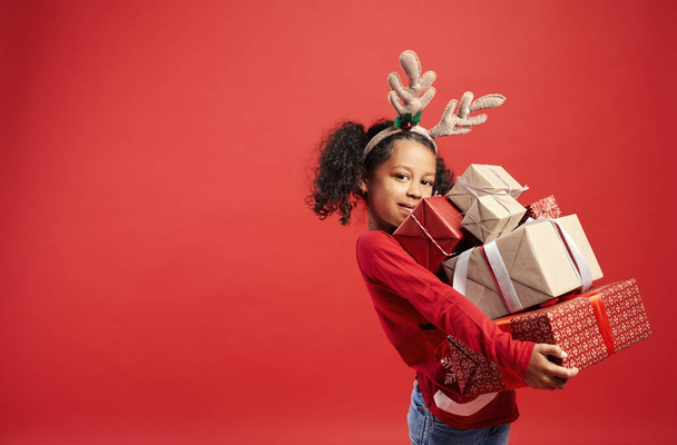 Porträt eines afrikanischen Mädchens mit einem Stapel Weihnachtsgeschenken - Foto, Bild