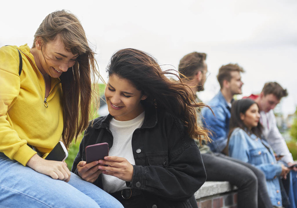 Две счастливые девушки смотрят на смартфон
  - Фото, изображение