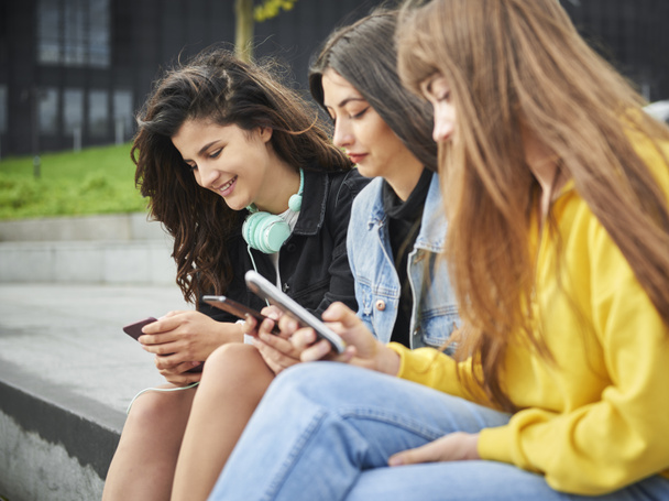 Widok z boku trzech dziewczyn korzystających ze smartfona  - Zdjęcie, obraz