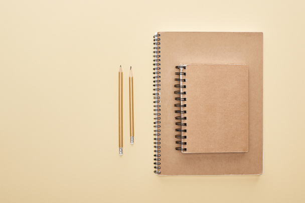 tendido plano con cuadernos en blanco de papel con lápices sobre fondo beige
 - Foto, imagen
