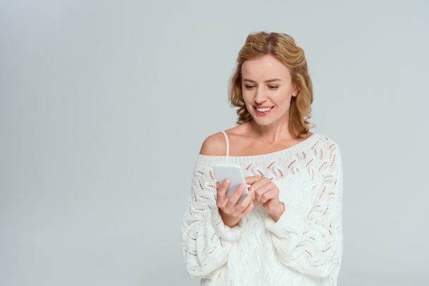 привлекательная и улыбающаяся женщина с помощью смартфона, изолированного на сером
  - Фото, изображение