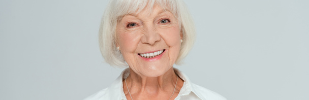 Panoramaaufnahme einer attraktiven und lächelnden Frau, die isoliert auf grau in die Kamera blickt  - Foto, Bild