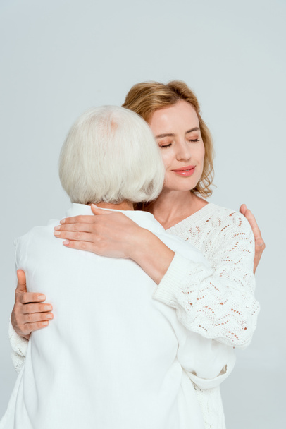 back view of mother hugging smiling daughter isolated on grey  - Foto, imagen