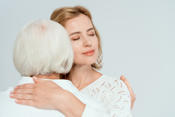 back view of mother hugging attractive daughter isolated on grey  - Photo, Image