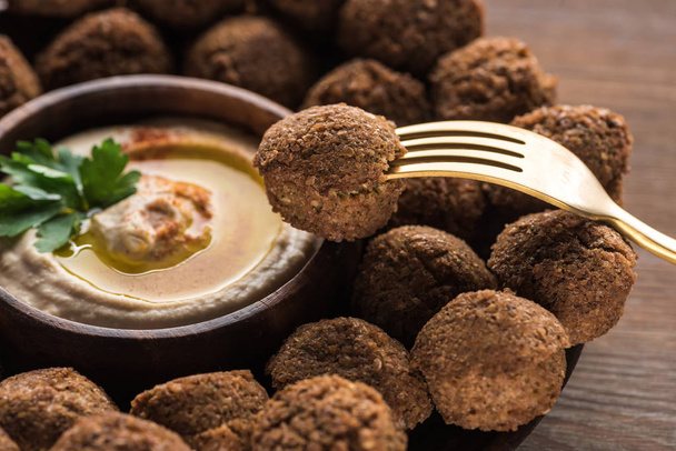 hummus and falafel served on wooden table with fork - Foto, imagen