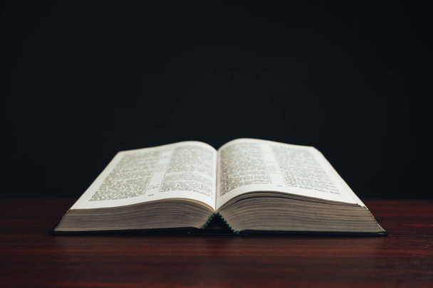 Biblia aberta em uma mesa de madeira vermelha. Belo fundo preto
. - Foto, Imagem