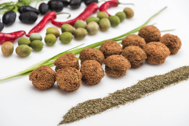 zblízka pohled na olivy, chilli paprika, zelená cibule, bylina a falafel na bílém pozadí - Fotografie, Obrázek