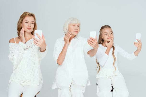 souriant petite-fille, mère et grand-mère prenant selfies et visages touchants isolés sur gris
  - Photo, image