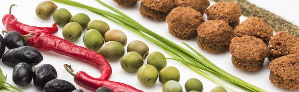 close-up zicht op peterselie, olijven, chili peper, groene ui, kruid en falafel op witte achtergrond, panoramisch schot - Foto, afbeelding