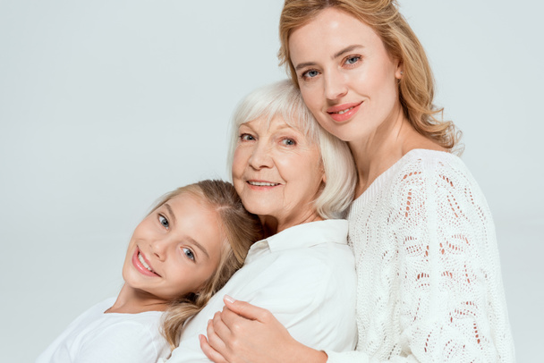 uśmiechnięta wnuczka, matka i babcia przytulają się na szaro  - Zdjęcie, obraz