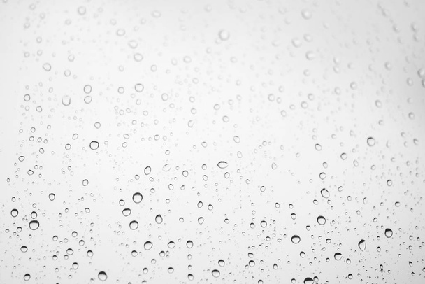 Window glass with drops of rain. Atmospheric light monochrome background with raindrops in bokeh - Photo, Image
