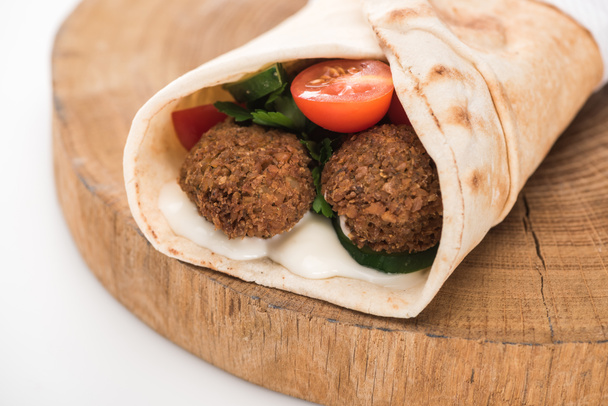 close up view of fresh falafel balls in pita with vegetables and sauce on wooden board on white background - Photo, Image