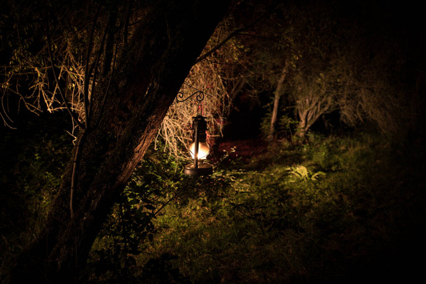 Horror Halloween koncepcji. Spalanie starej lampy olejowej w lesie w nocy. Nocne dekoracje sceny koszmaru. - Zdjęcie, obraz