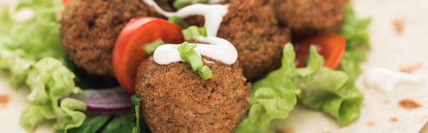 close up view of fresh falafel balls on pita with vegetables and sauce, panoramic shot - Fotoğraf, Görsel