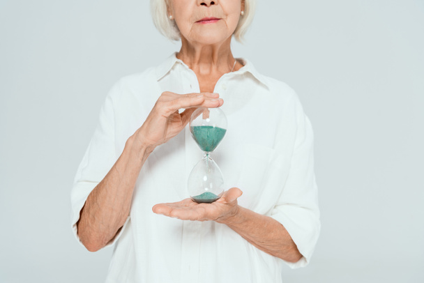 vista recortada de la mujer sosteniendo reloj de arena aislado en gris
  - Foto, Imagen