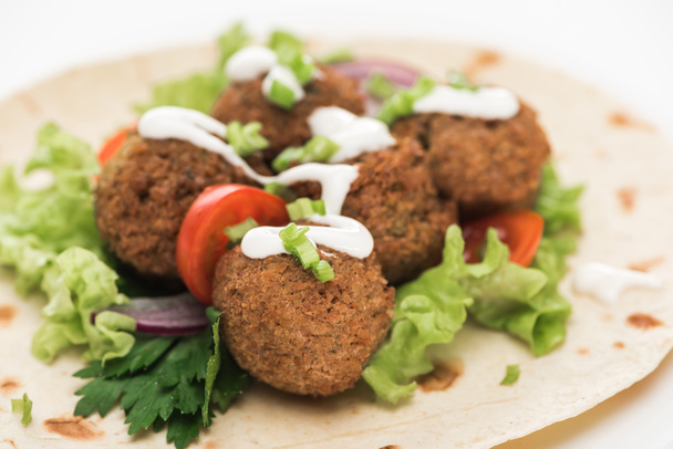 close up view of fresh falafel balls on pita with vegetables and sauce on white background - Фото, зображення