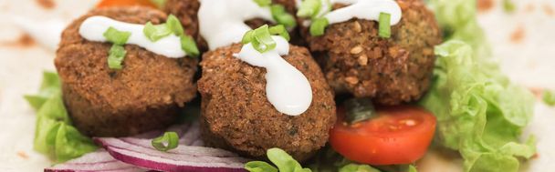 close up view of fresh falafel balls on pita with vegetables and sauce, panoramic shot - Foto, afbeelding