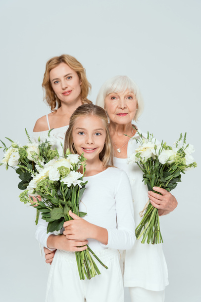smiling granddaughter, mother and grandmother holding bouquets isolated on grey  - Φωτογραφία, εικόνα
