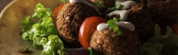 close up view of falafel with sauce on pita with vegetables in darkness, panoramic shot - Photo, Image