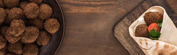 вид сверху на фалафель с овощами и соусом в пите на деревянном столе, панорамный снимок
 - Фото, изображение