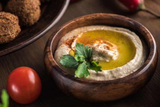 close up view of delicious falafel balls near hummus with parsley on wooden table - Фото, зображення