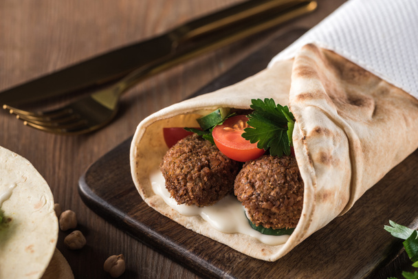 close up view of falafel with vegetables and sauce in pita on wooden table - Foto, immagini