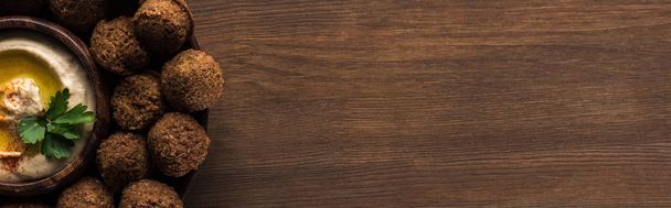 πάνω όψη από μπάλες φαλάφελ με χούμους στο πιάτο σε ξύλινο τραπέζι με χώρο αντιγραφής, πανοραμική λήψη - Φωτογραφία, εικόνα