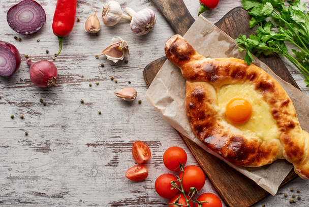 Adjarian khachapuri with vegetables, spices and cilantro on table - Photo, image