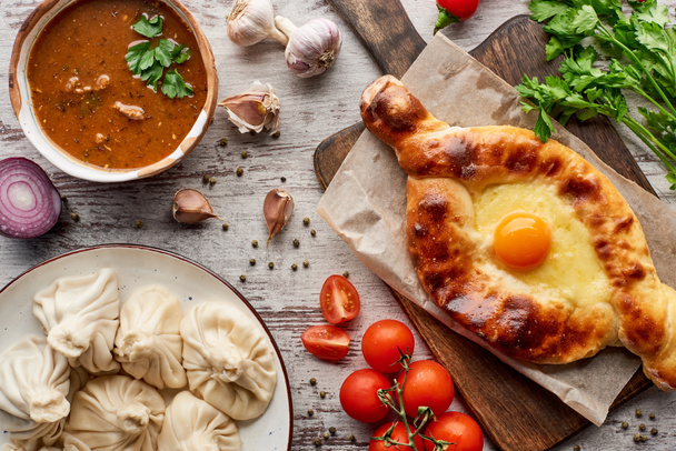 Traditional adjarian khachapuri, soup kharcho and khinkali with vegetables and spices on table - 写真・画像