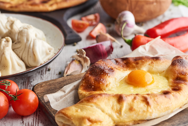 Selective focus of adjarian khachapuri and khinkali on table with vegetables - 写真・画像