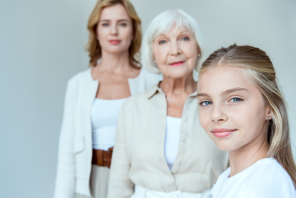 вибірковий фокус усміхненої онуки і бабусі, мати на фоні ізольована на сірому
  - Фото, зображення