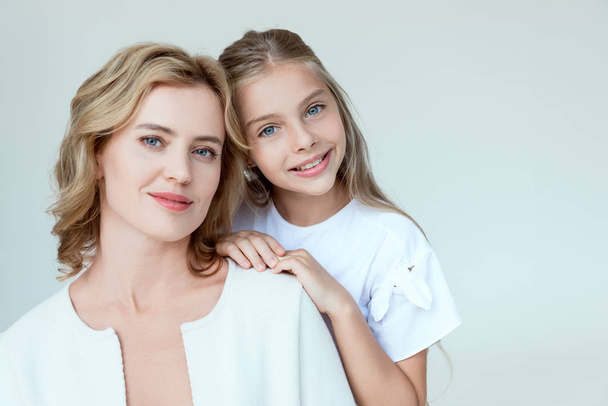 attractive mother and smiling daughter looking at camera isolated on grey  - Foto, Bild