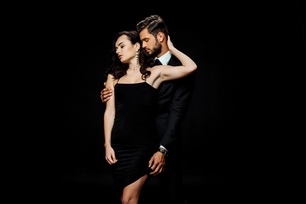 bearded man with closed eyes touching dress of girlfriend isolated on black  - Fotografie, Obrázek
