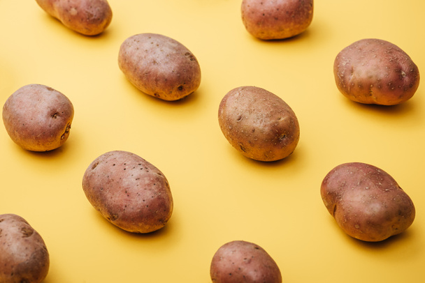 pattern of raw whole fresh potatoes on yellow background - Photo, Image