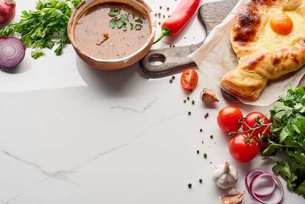 Adjarian khachapuri and soup kharcho with vegetables on marble texture - Photo, Image