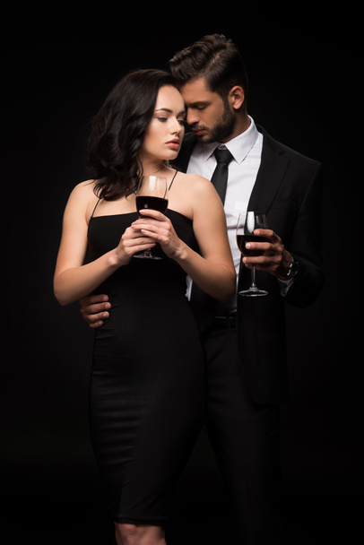 hombre barbudo y atractiva chica sosteniendo vasos con vino tinto aislado en negro
  - Foto, Imagen
