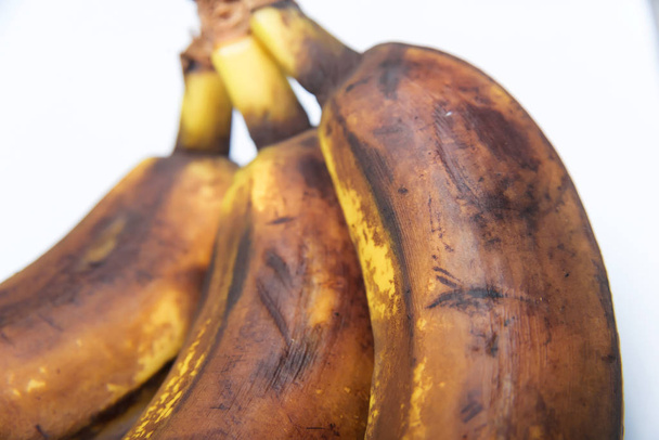 バナナの皮が黒くなった。白い背景に熟れたバナナの束。果物やバナナの不適切な保管 - 写真・画像