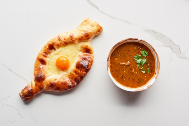 Top view of adjarian khachapuri and soup kharcho on marble texture - Foto, afbeelding