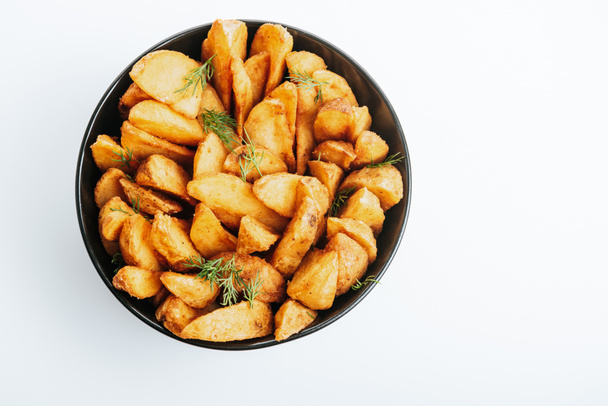 bovenaanzicht van heerlijke gouden aardappelpartjes met dille in schaal geïsoleerd op wit - Foto, afbeelding