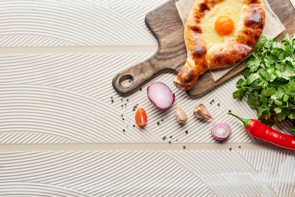 Top view of adjarian khachapuri with vegetables and cilantro on textured background - Foto, Imagem
