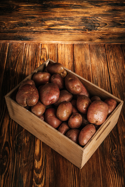 fresh ripe potatoes in box on wooden background - Foto, Imagem