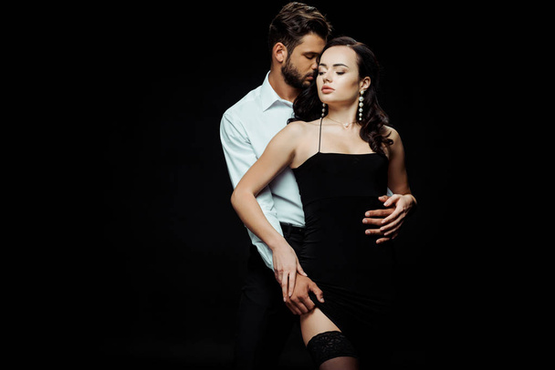 vášnivý muž dotýká sexy dívka v šatech izolovaných na černé  - Fotografie, Obrázek