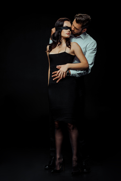 handsome man looking at blindfolded woman on black  - Fotografie, Obrázek