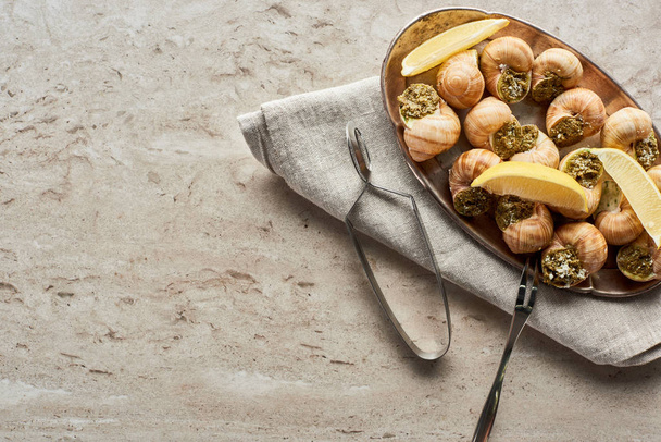 top view of delicious served escargots with lemon on stone background - 写真・画像