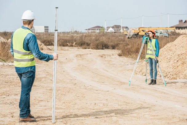 Surveyors with digital level and survey ruler working on dirt road - Photo, Image