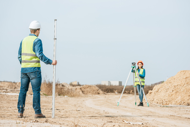 Surveyors utilisant le niveau numérique et règle d'enquête sur la route de terre
 - Photo, image