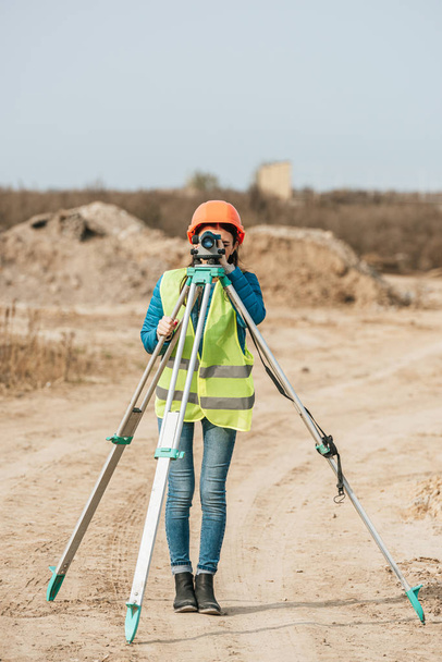 Female surveyor using digital level on dirt road  - Photo, Image