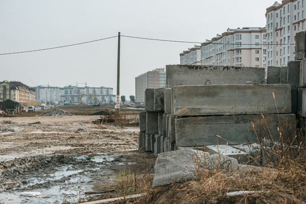 Бетонні блоки на брудній дорозі та будівельному майданчику на фоні
 - Фото, зображення