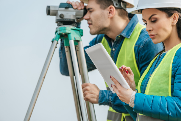 Selective focus on surveyor with tablet and colleague with digital level - Photo, Image